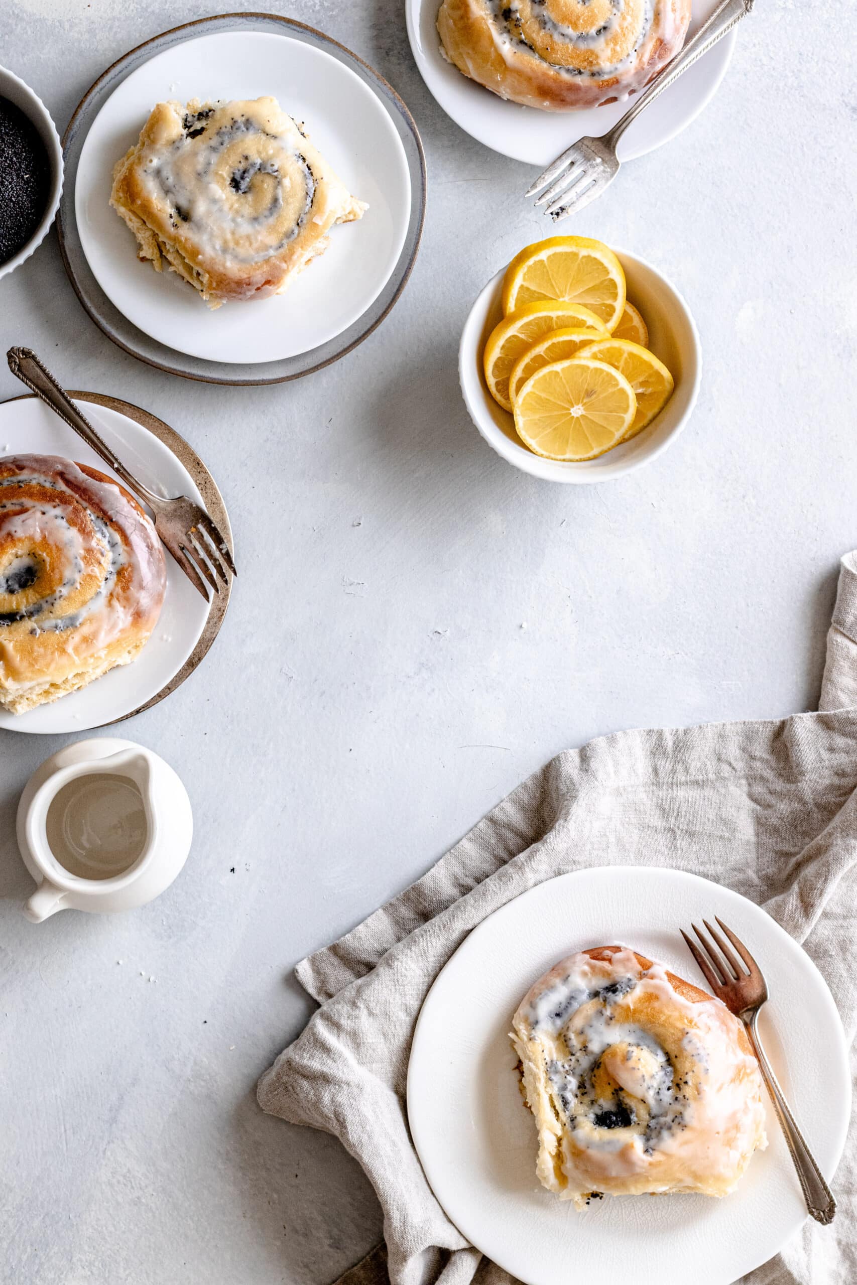 Image of a table scape with iced lemon poppy seed buns. 