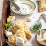 Image of herbed scones with extra kräuter quark dip on a baking sheet with parchment paper.