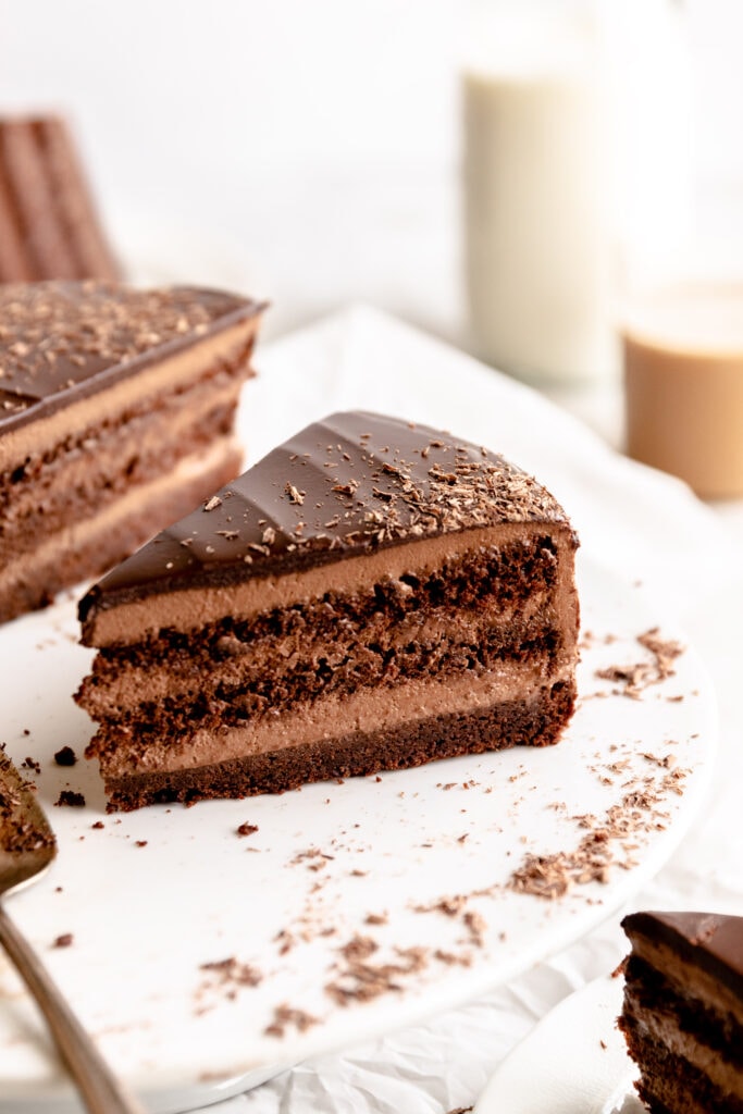 Up close image of a slice of chocolate mousse cake on a white cake stand.
