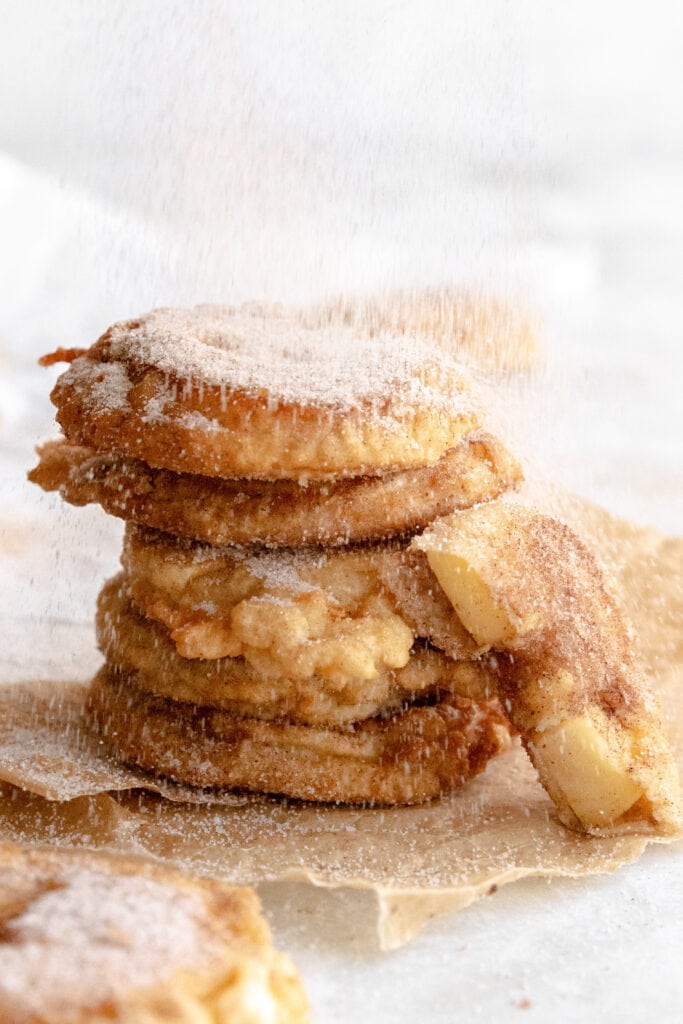 Tower of 5 Apfel ringe being showered with cinnamon sugar.
