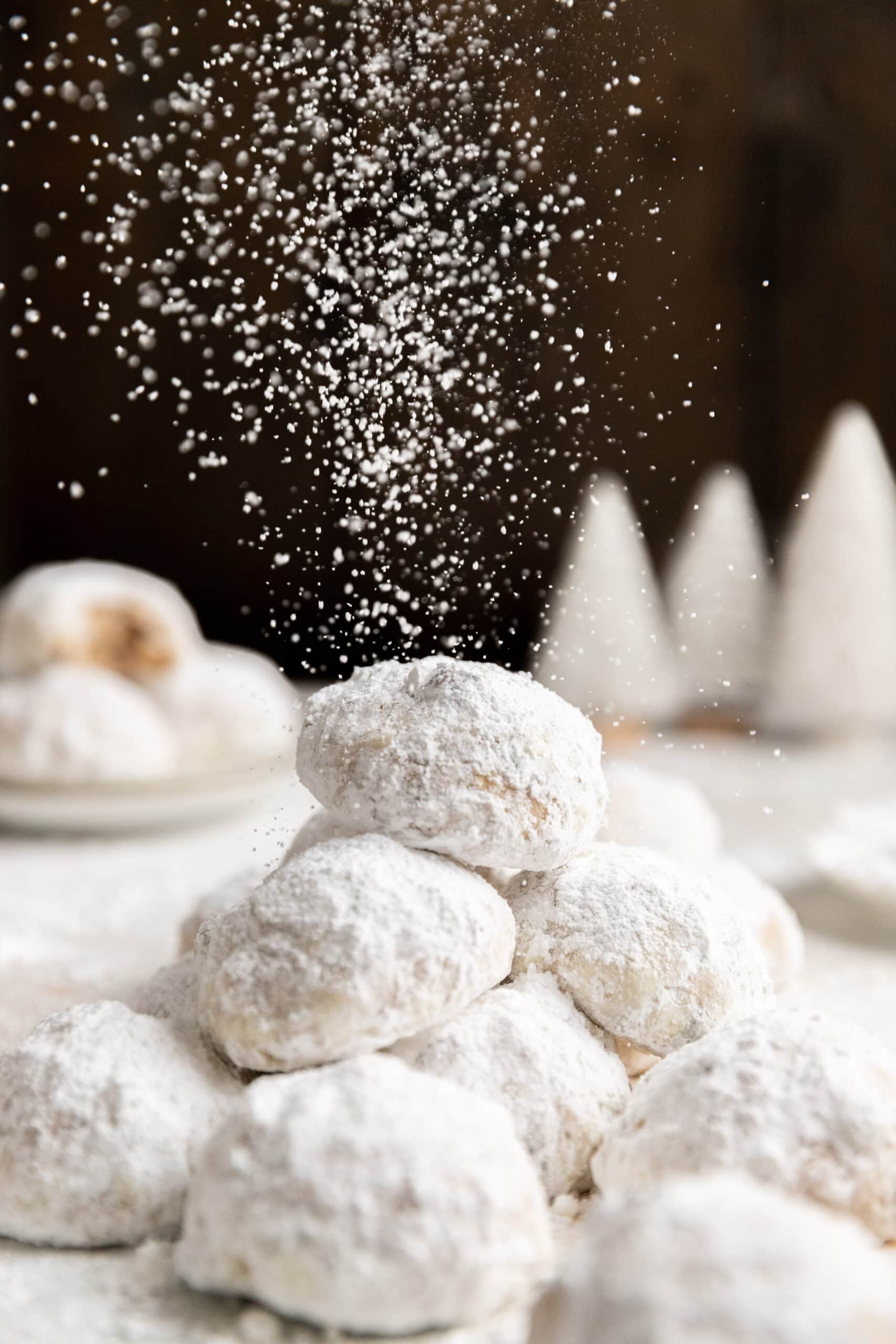 Side view of a stack of stollen balls being dusted with powdered sugar.