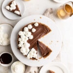 Overhead image of a no bake chocolate tart on a white cake stand with a few slices cut out.
