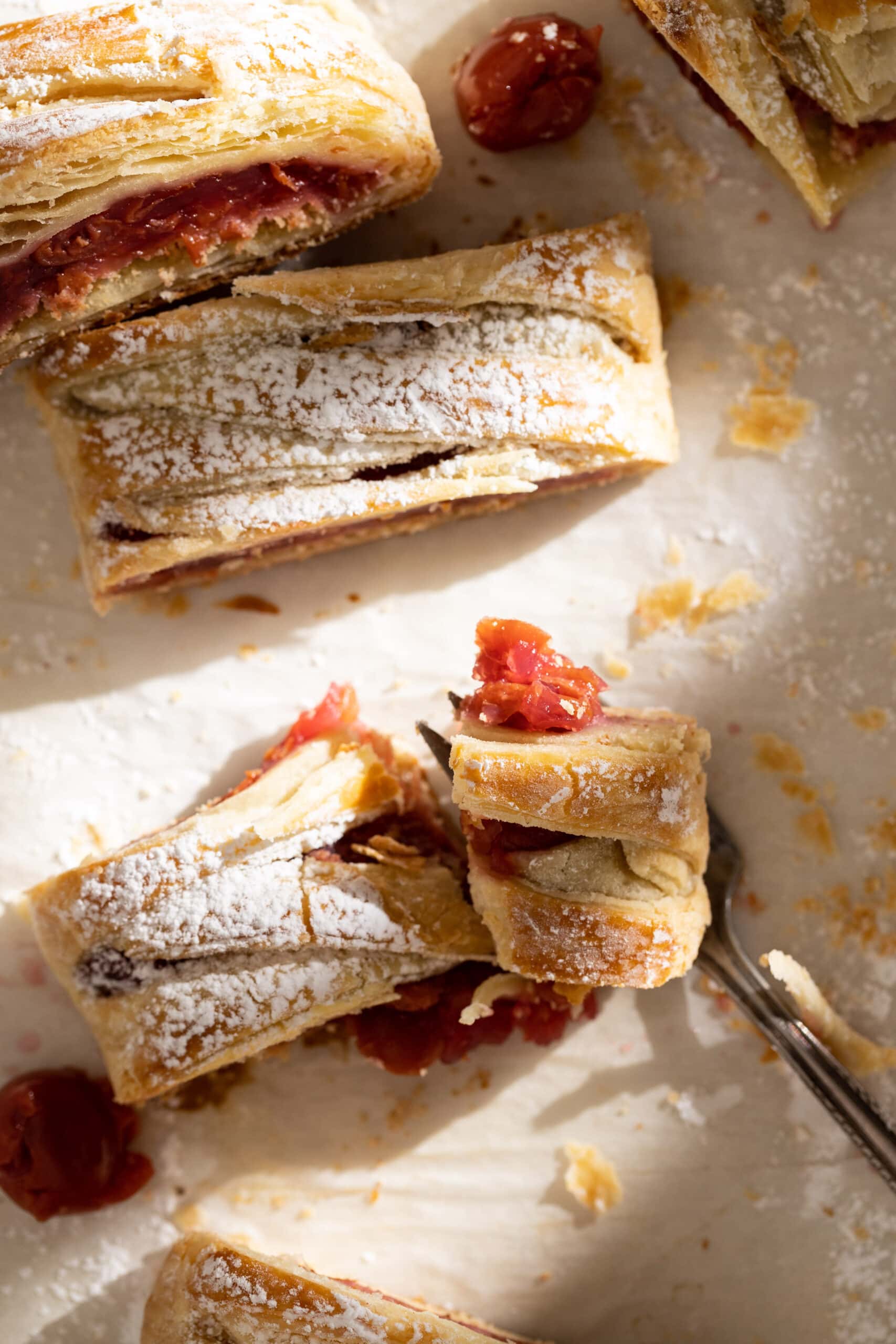 Overhead view of multiple slices of cherry strudel on parchment paper.