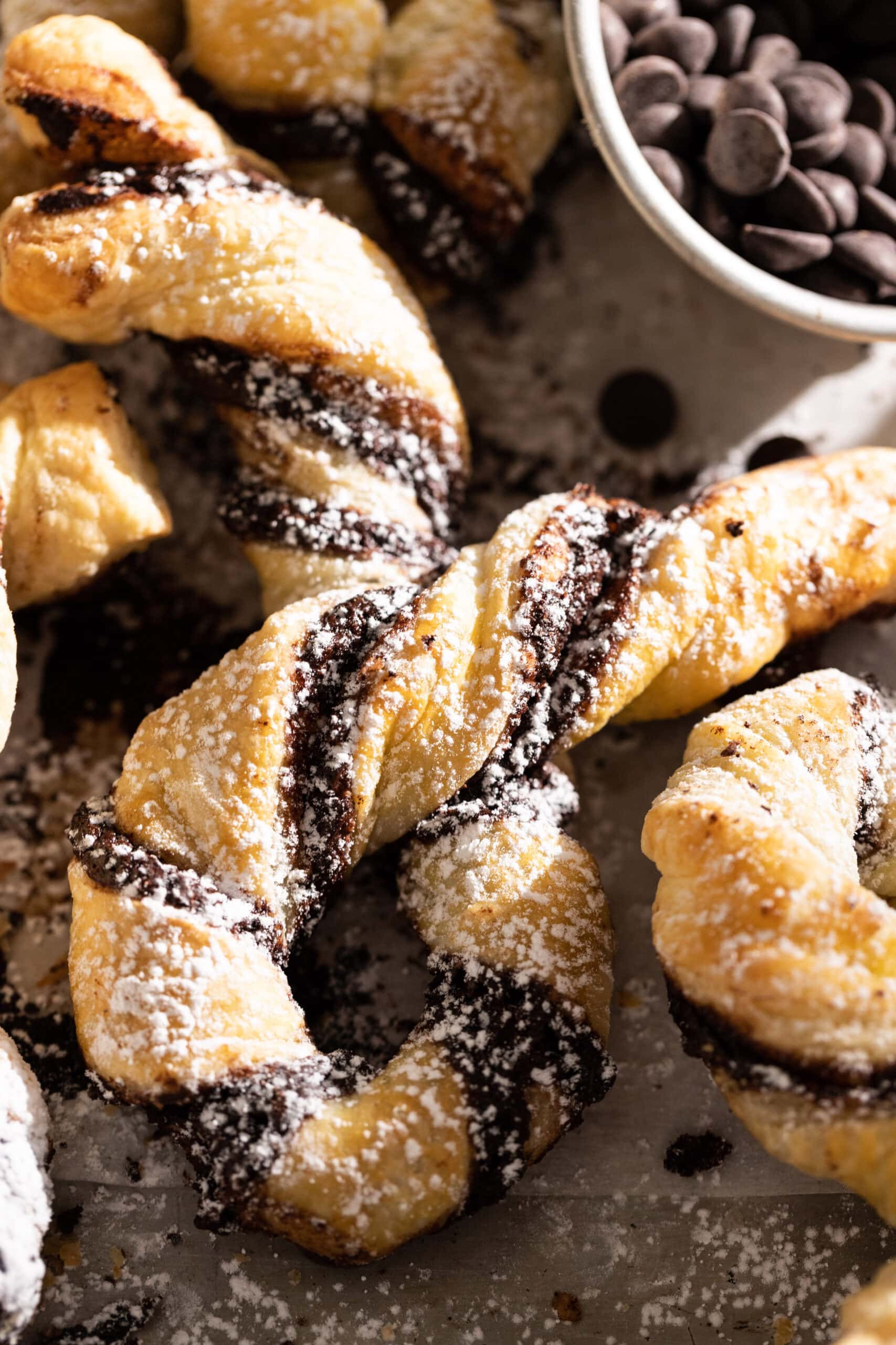 Up close image of a chocolate pastry twist dusted with powdered sugar.