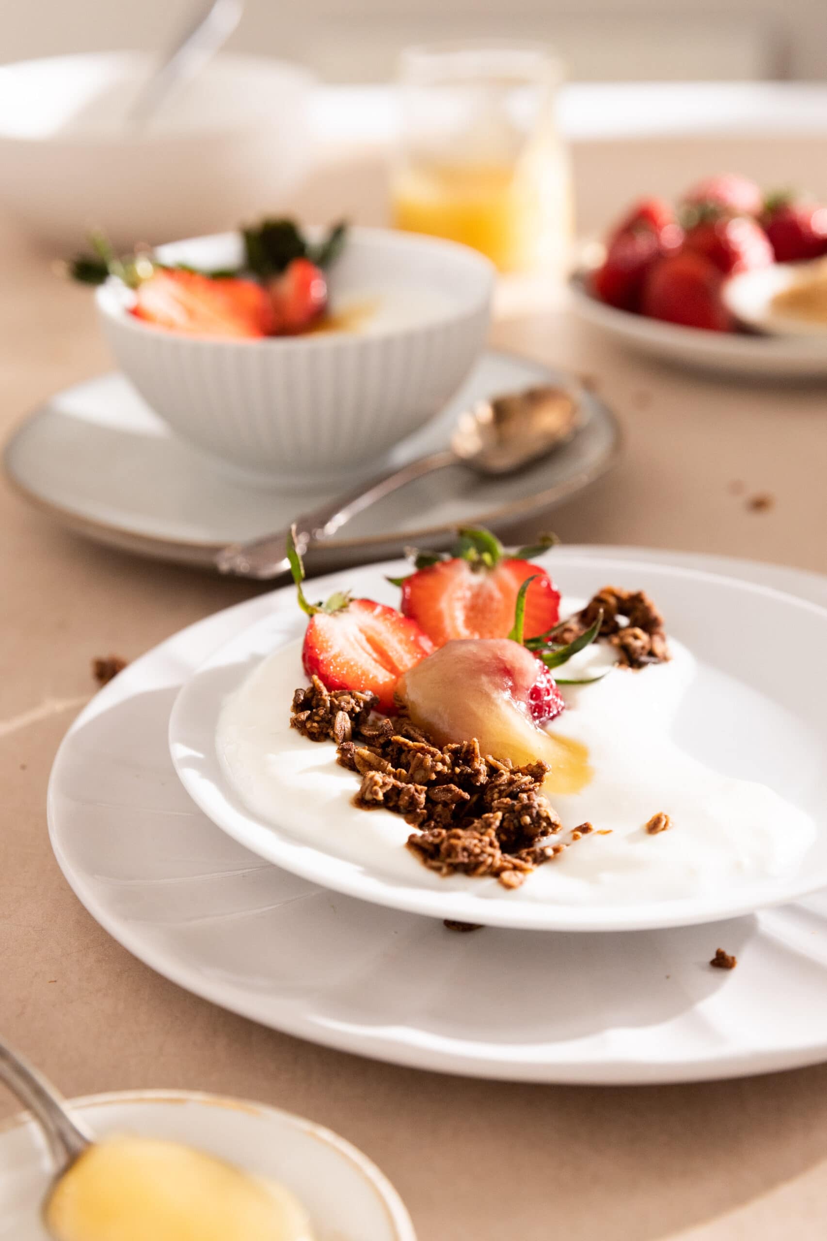 Side view of a table with quark, topped with granola, strawberries and whipped honey.