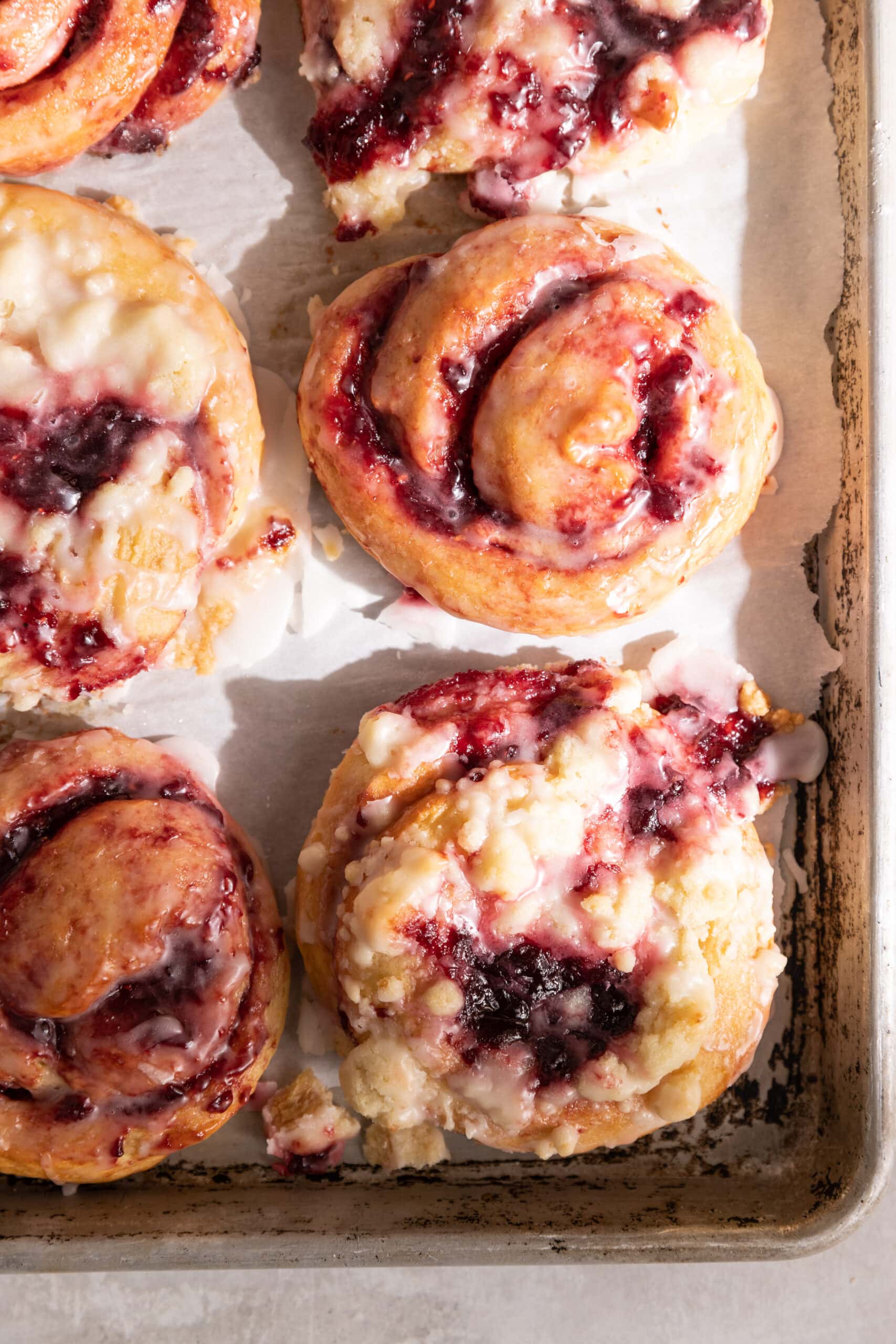 Overhead image of six cherry sweet rolls on a parchment lined baking sheet.