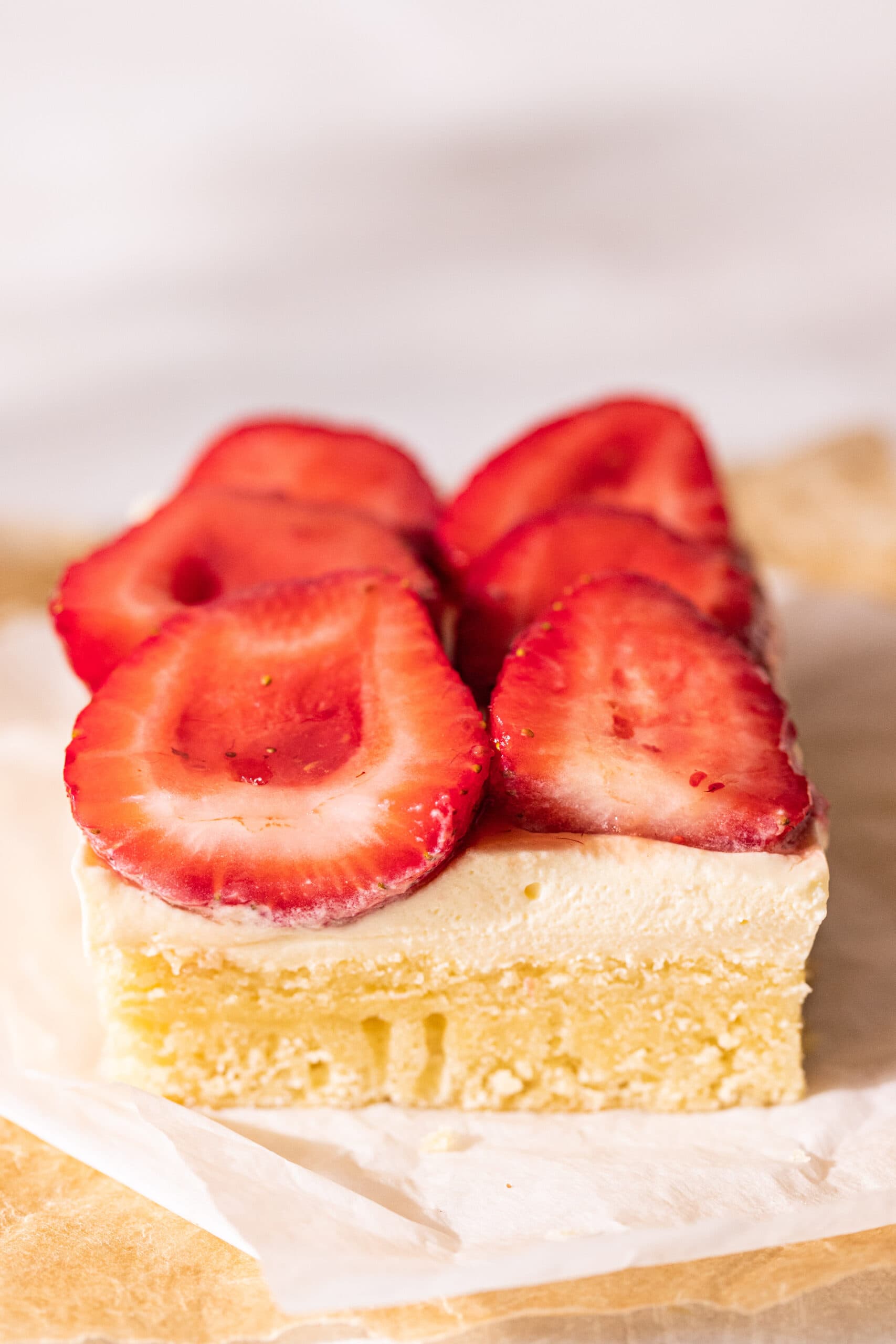 Cross section view of strawberry and cream cake where the vanilla cake, cream, and strawberries are visible.