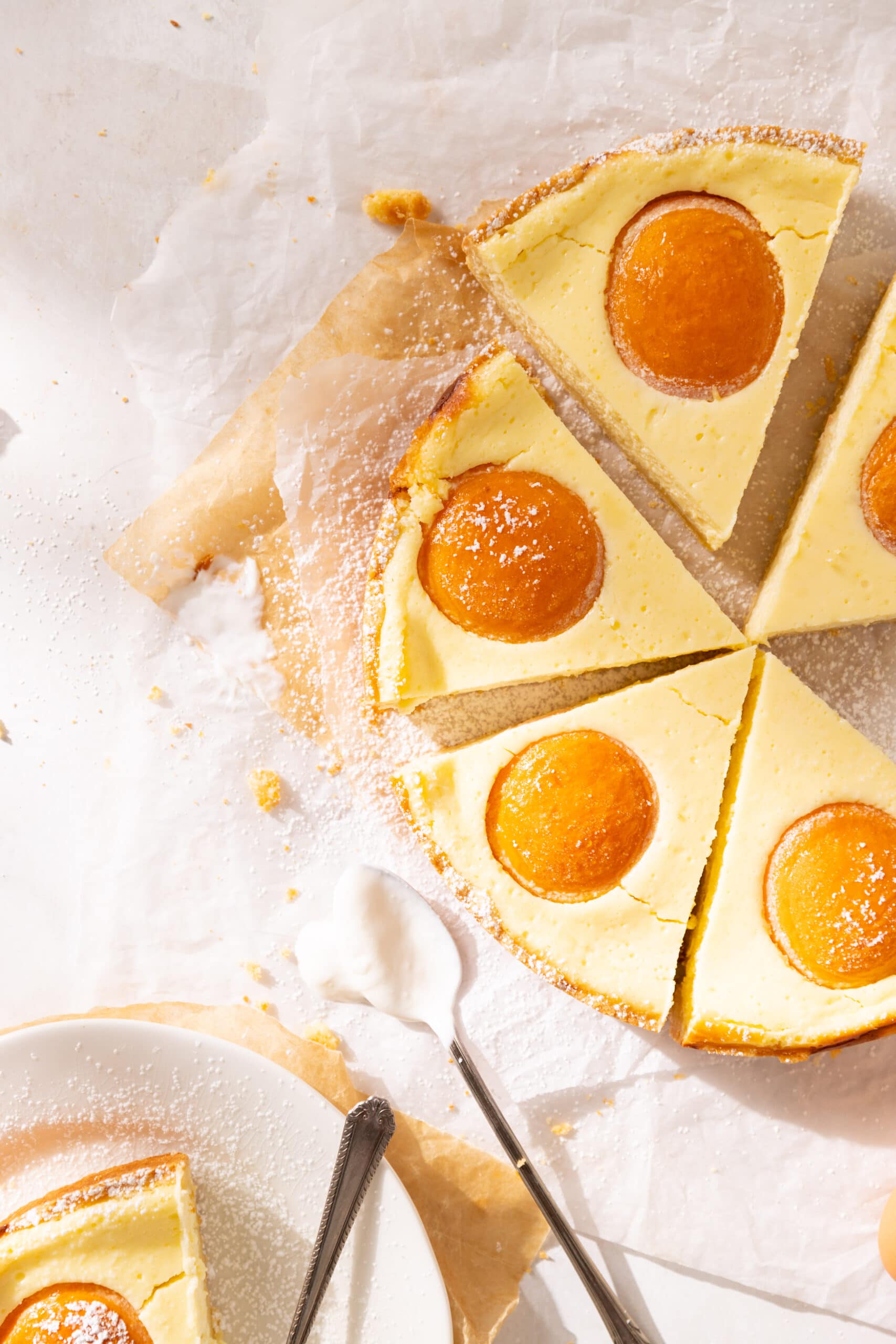 Overhead view of multiple slices of german apricot cheesecake with one slice on a white plate.