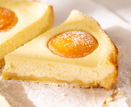 Side view of a slice of German Apricot Cake on white parchment paper.