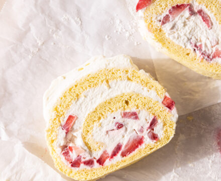 Overhead view of slices of Erdbeerroulade with the whipped cream and strawberries showing.