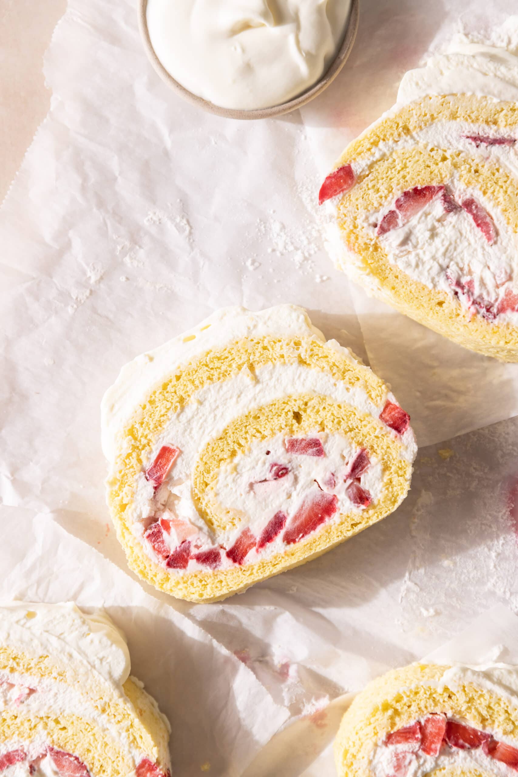 Overhead view of slices of Erdbeerroulade with the whipped cream and strawberries showing. 