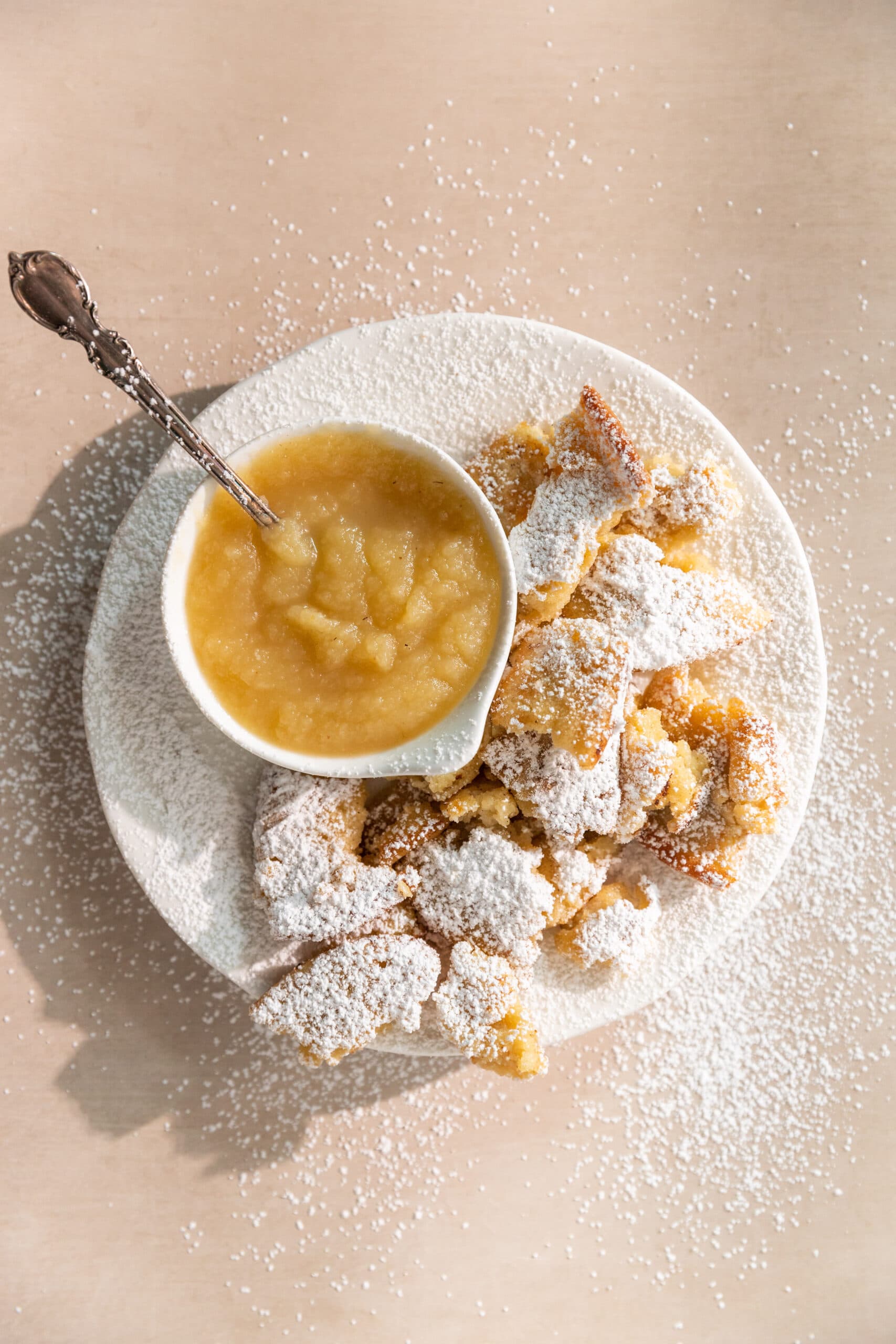 Overhead view of Kaiserschmarrn, an Austrian torn up pancake topped with powdered sugar and served with applesauce.