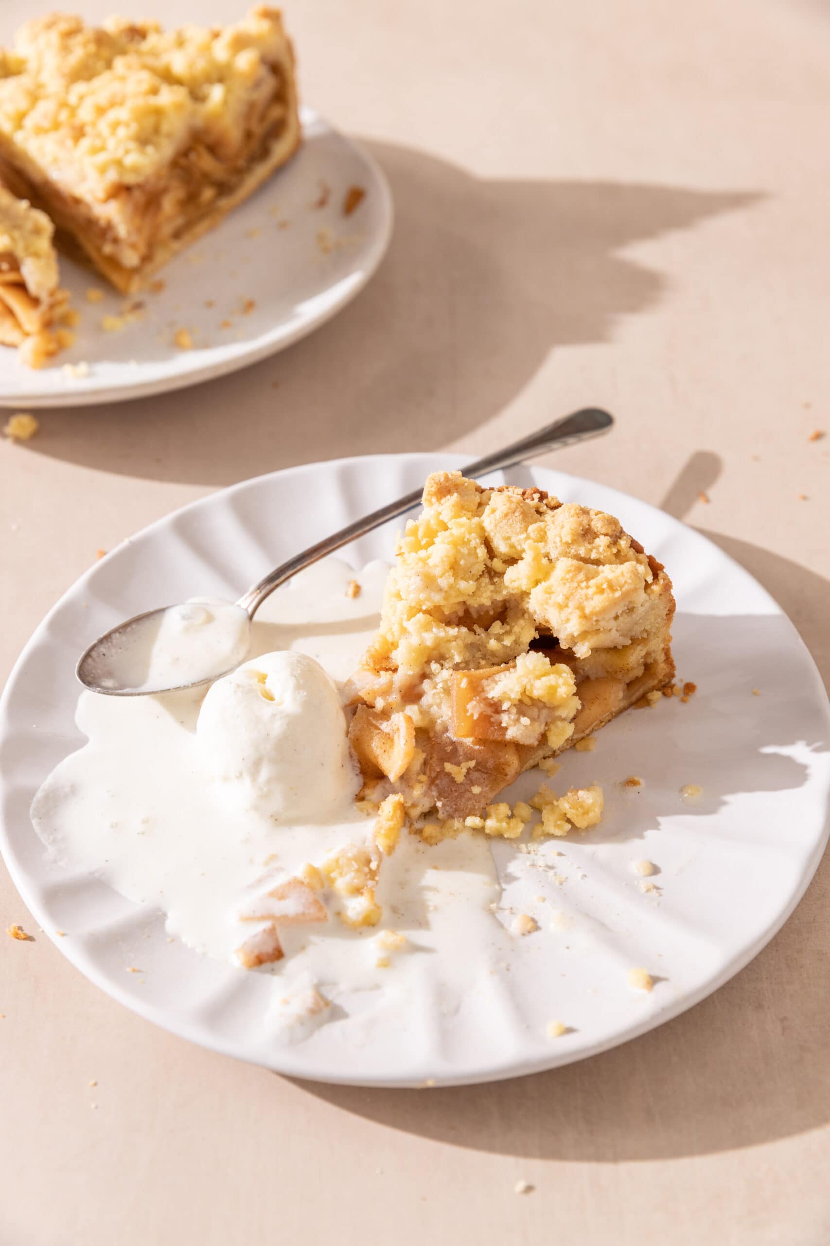 Slice of apple streusel pie with a side of vanilla ice cream.