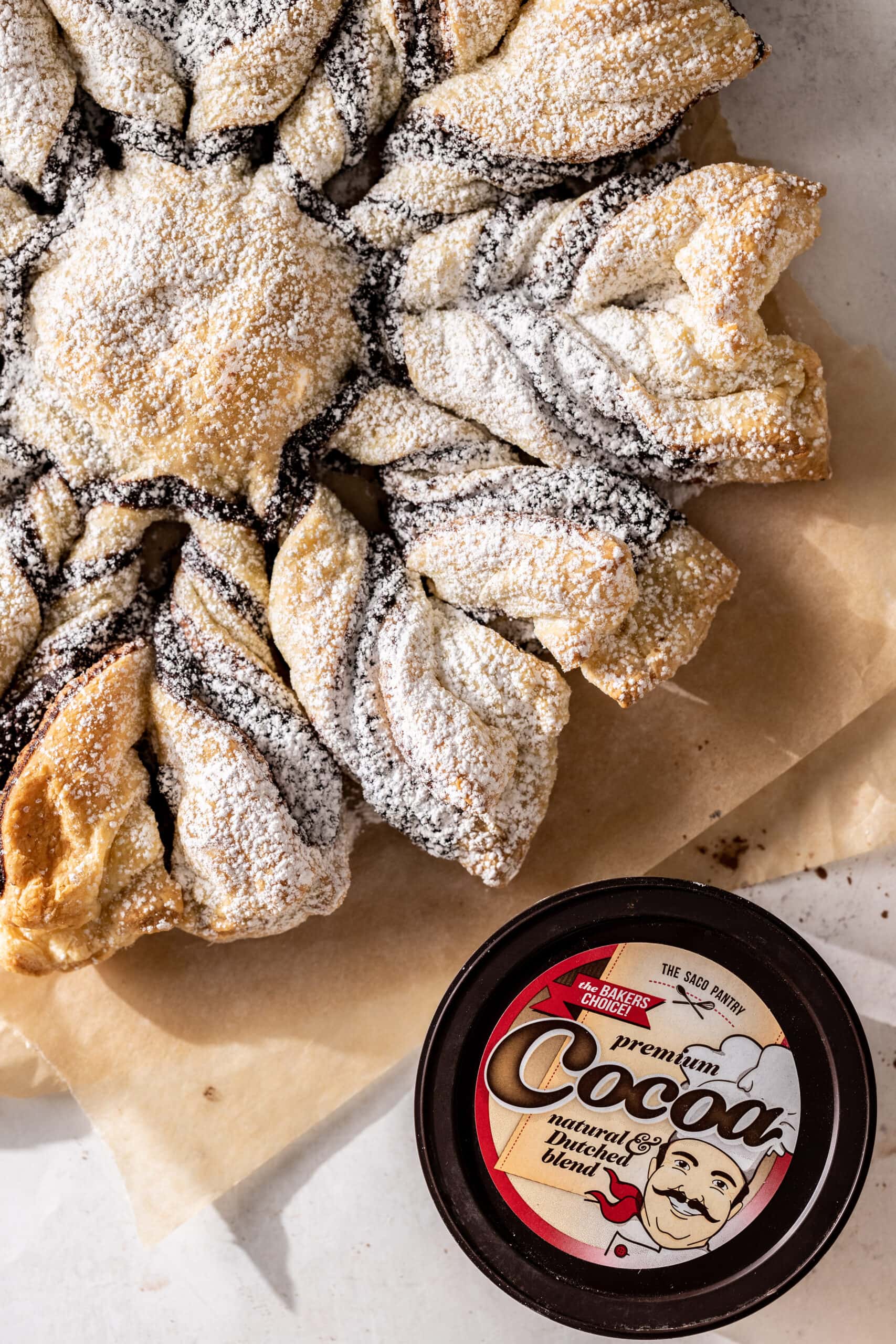 Overhead view of a chocolate puff pastry snowflake with Saco Pantry premium cocoa powder. 