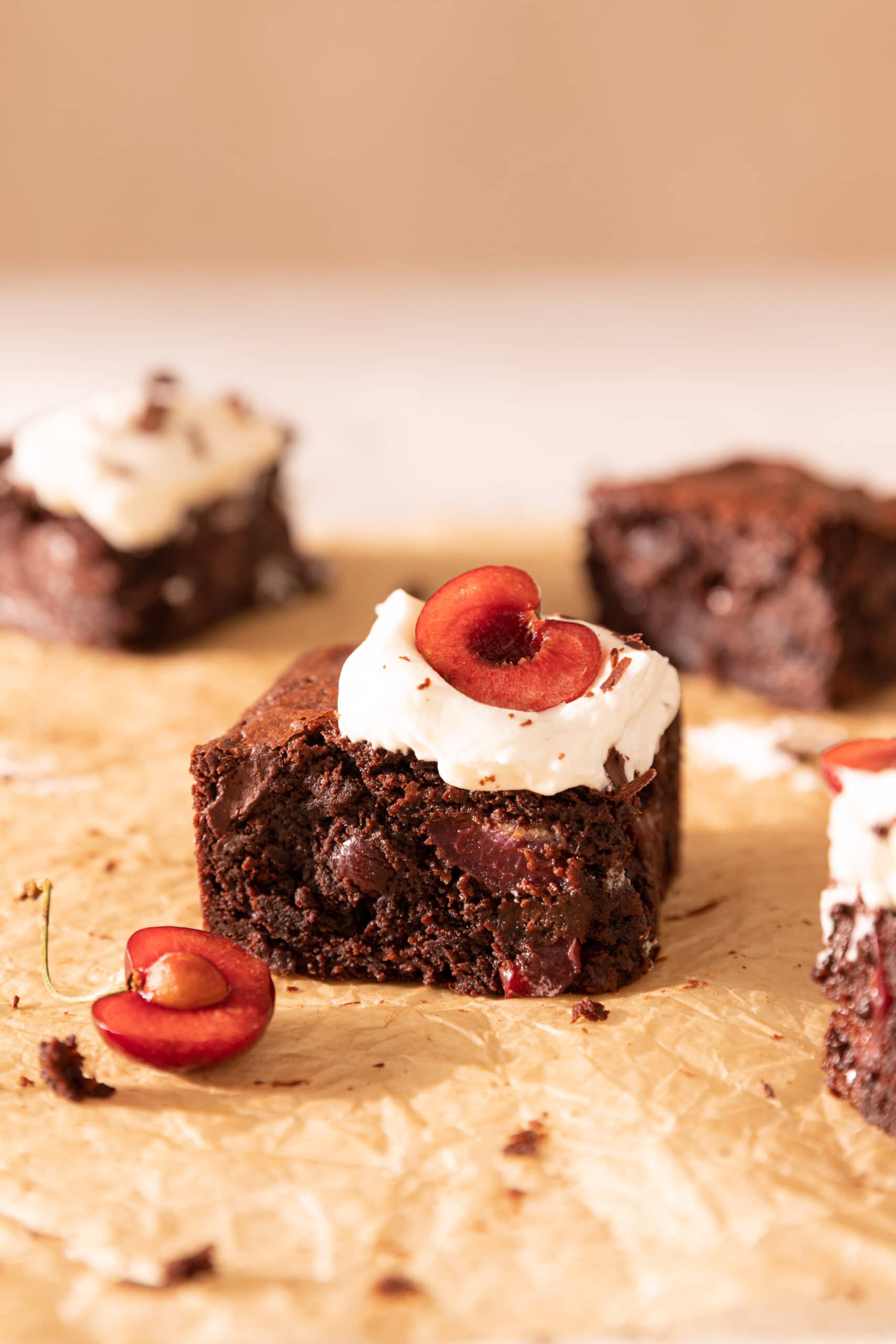 Side view of a square slice of Black Forest brownie with whipped cream on top. 
