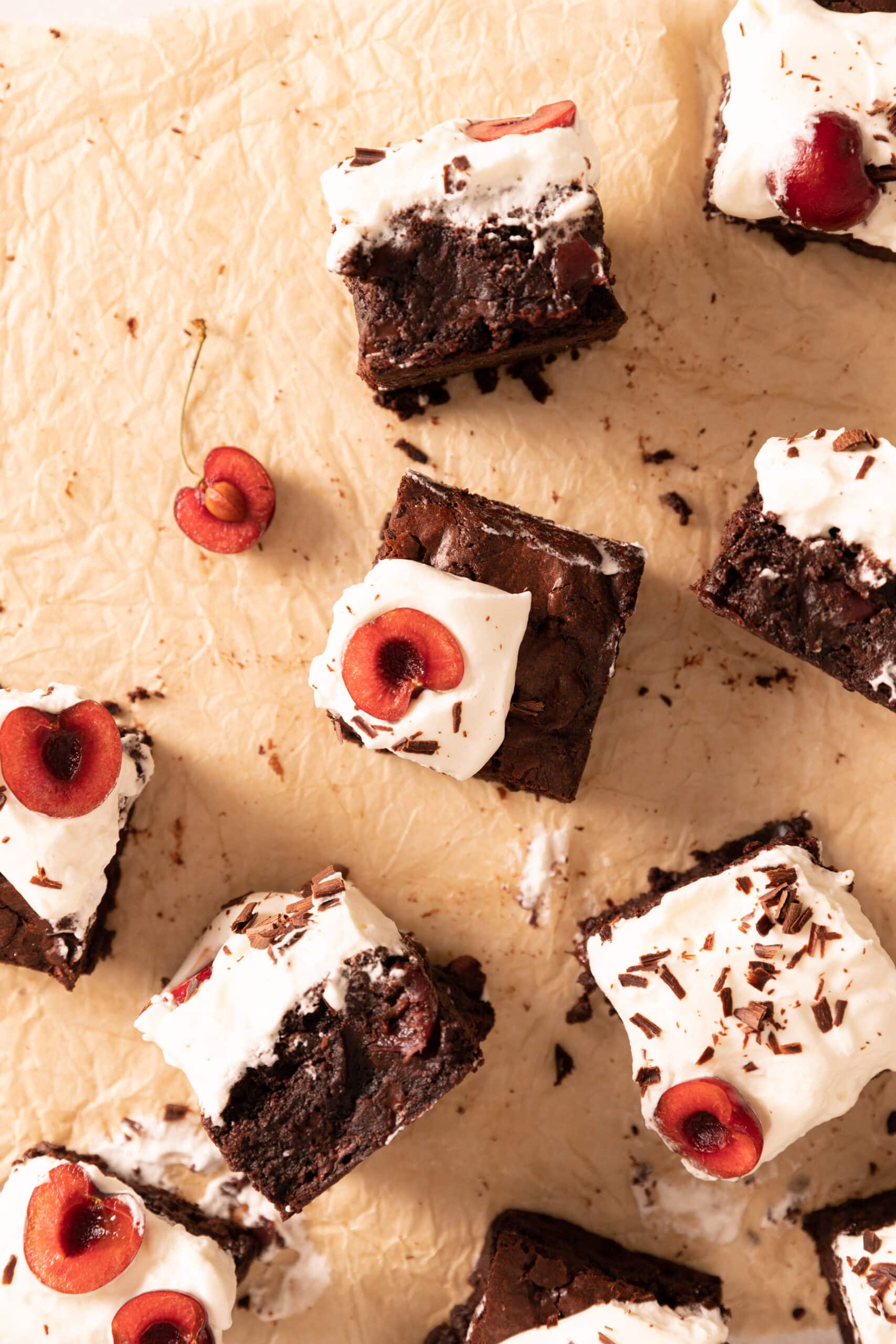 Overhead view of multiple squares of black forest brownies with whipped cream and cherries. 