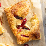 Puff pastry cherry hand pie cut in half on baking parchment paper.