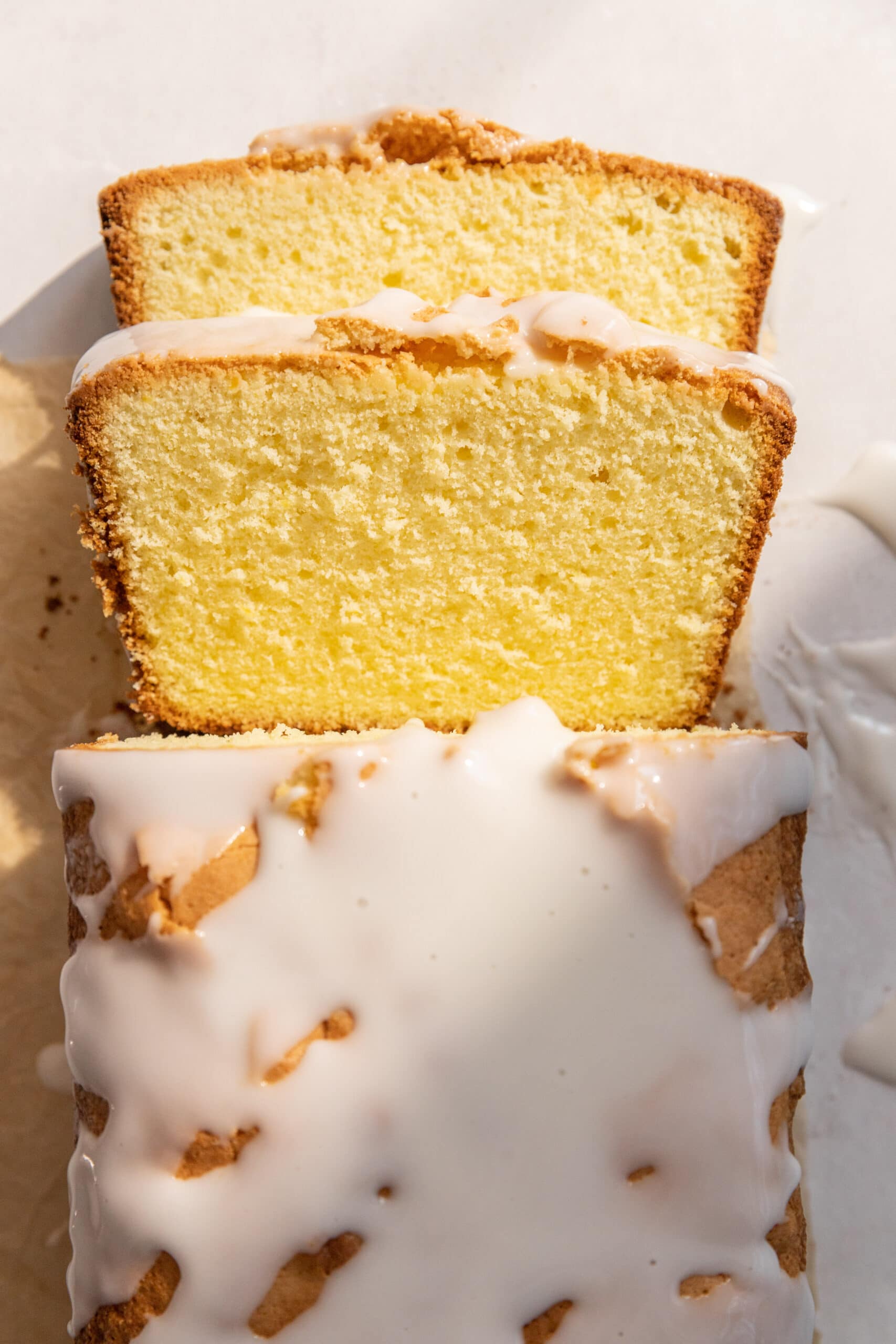 Lemon loaf cake with lemon glaze with 2 slices cut showing the tender crumb inside. 
