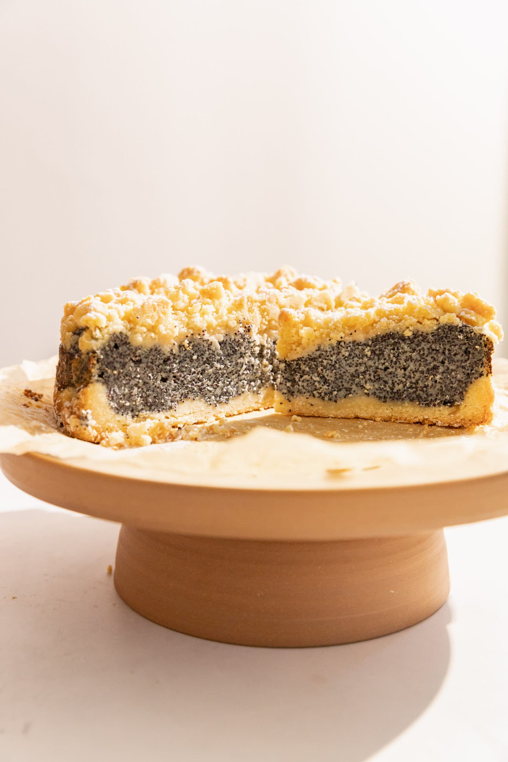 Mohnkuchen on a ceramic cake stand  cut into so that they poppyseed filling is visible. 