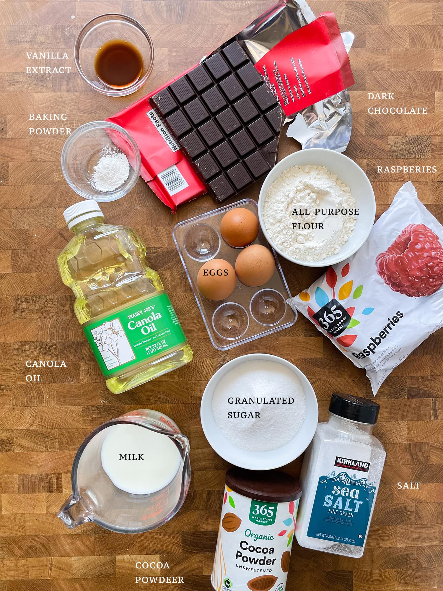 All ingredients needed to make a Chocolate Raspberry Cake laid out on a table and labeled. 
