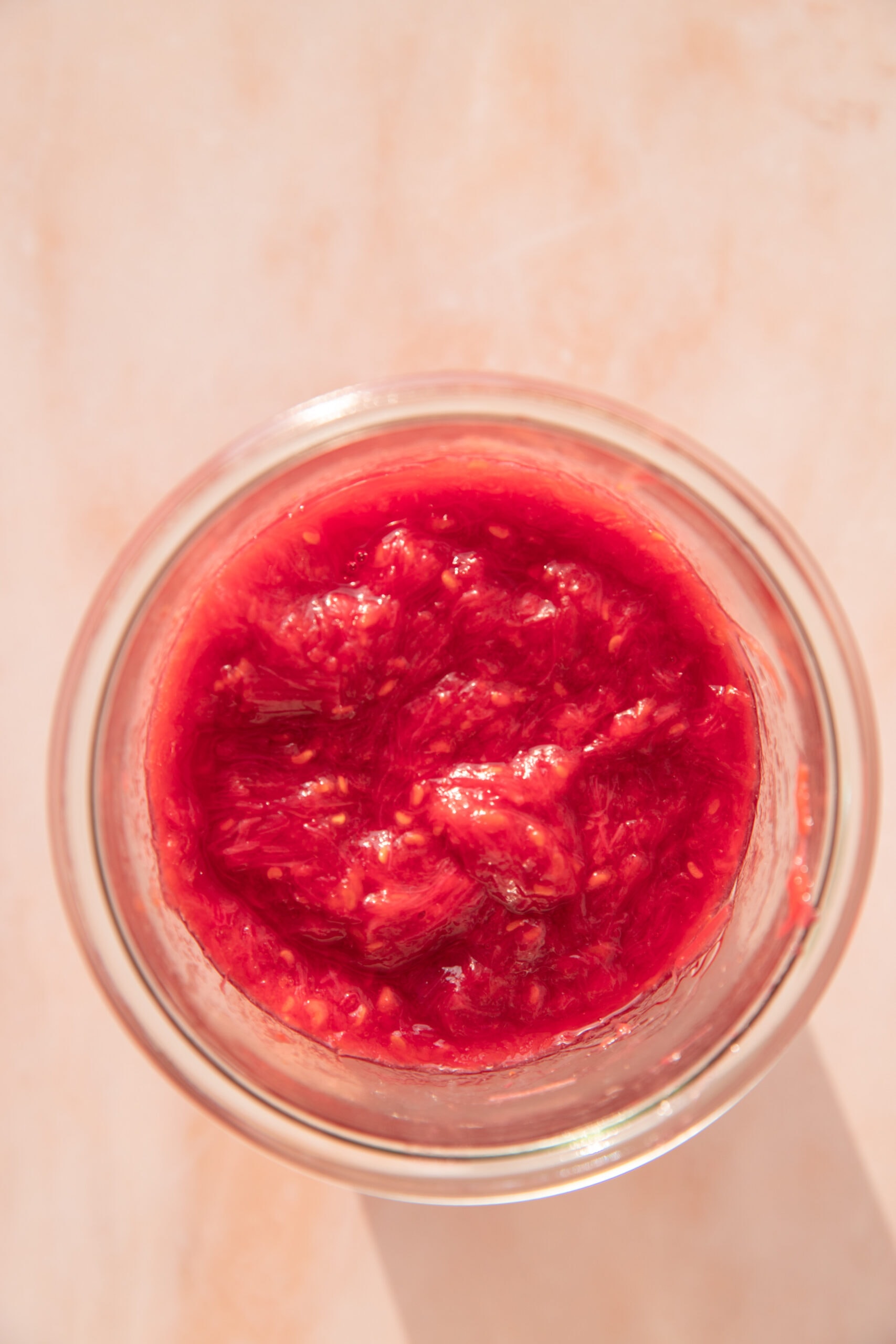 Overhead view of rhubarb compote in a glass jar. 