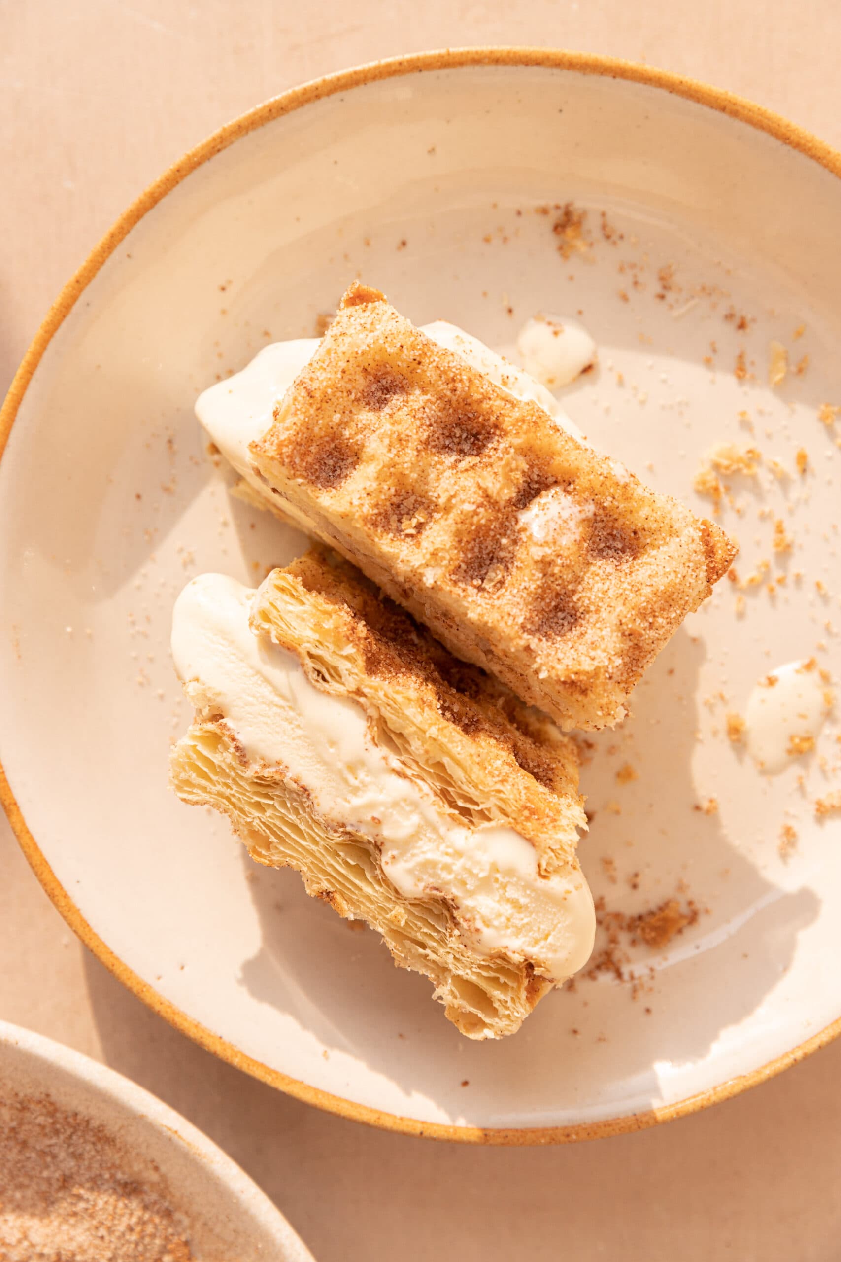 Puff Pastry Waffle Ice Cream Sandwich cut in half so the cross section is visible on a white plate. 