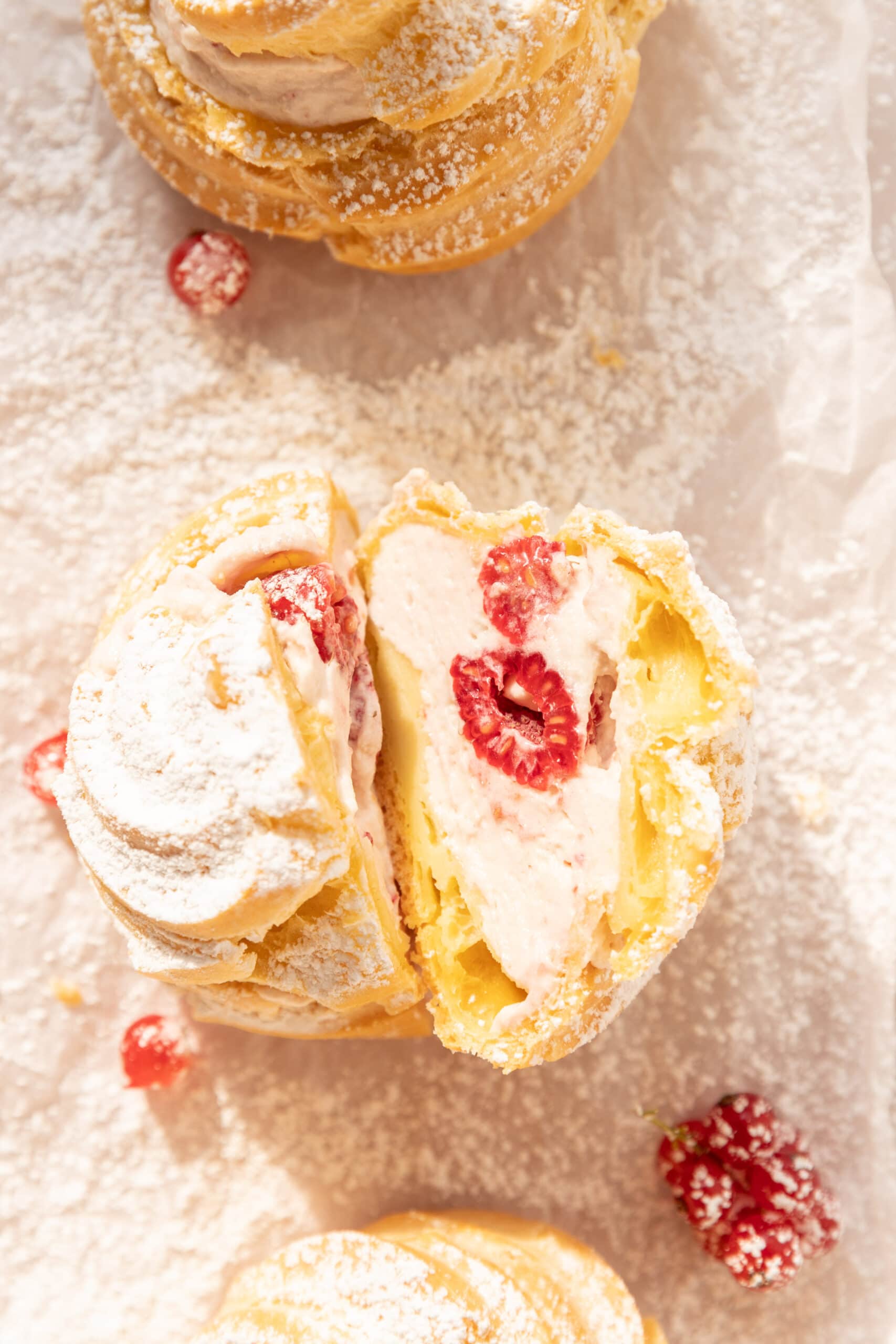 Overhead view of a cream puff filled with raspberry whipped cream, cut in half so the filling is showing.