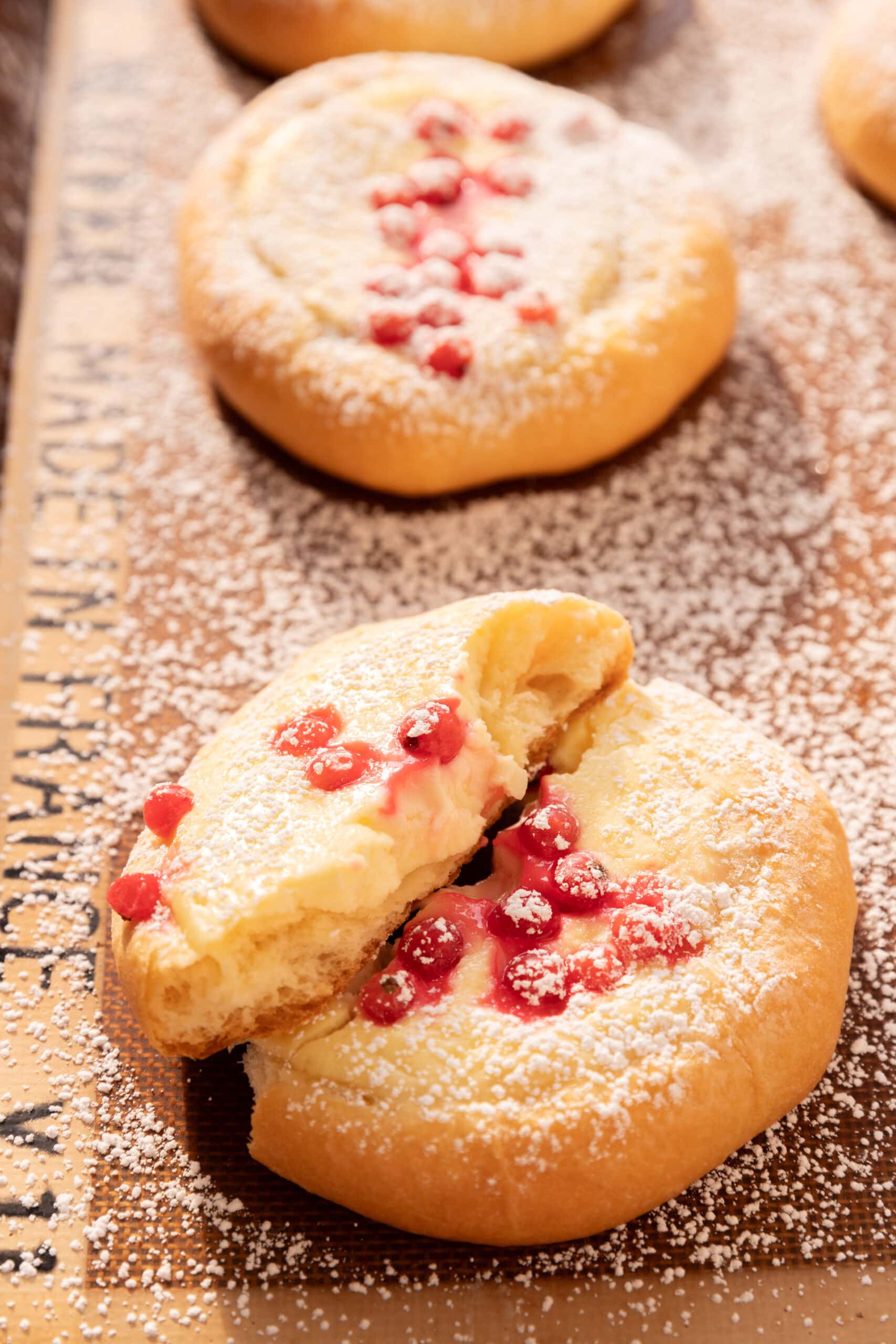 Angled view of quarkteilchen with red currants dusted with powdered sugar and torn in half. 
