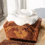Spiced marble loaf cake with slices cut so the swirl is visible, topped with a nutmeg whipped cream and flaky sea salt.