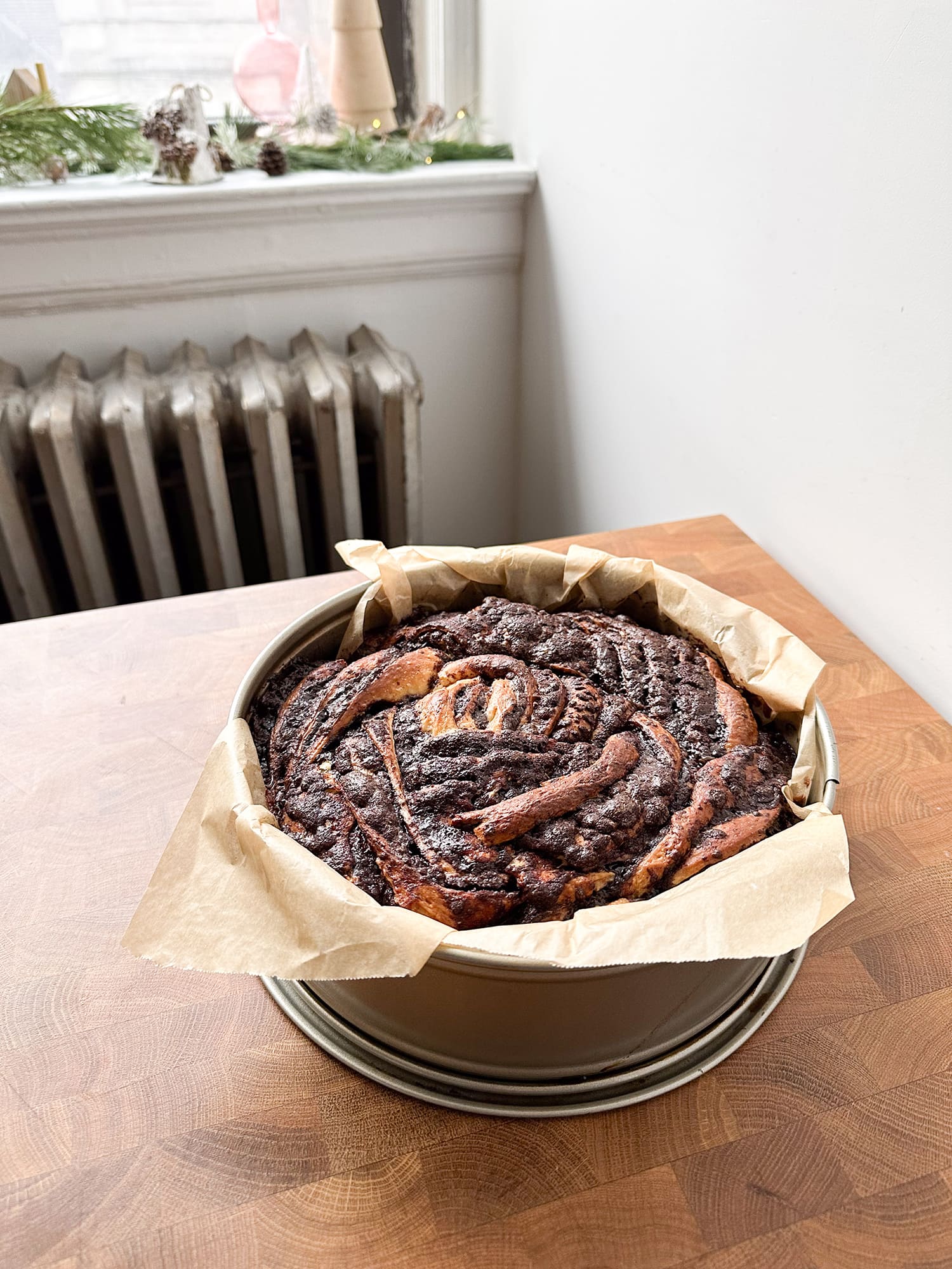 Fully baked chocolate cinnamon roll inside of a parchment lined springform pan. 