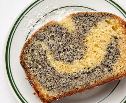A slice of lemon poppyseed cake on a white and green plate.