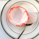 Overhead view of a blood orange posset with a spoonful taken out on a white and green plate.