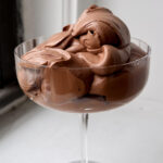 Dollops of dark chocolate mousse in a coupe glass.