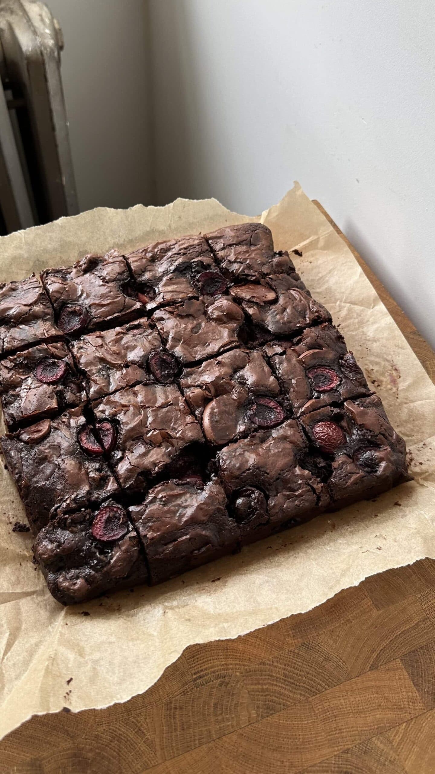 Black Forest Brownies cut into 16 on a sheet of brown parchment paper. 