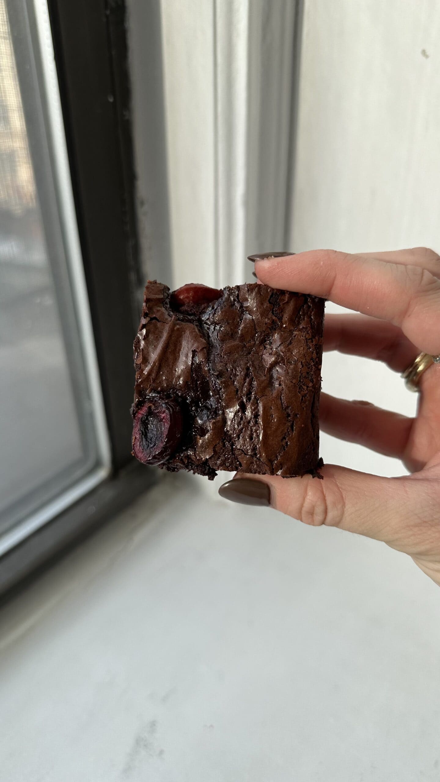 One Black forest brownie being held up so the crinkle top is visible.
