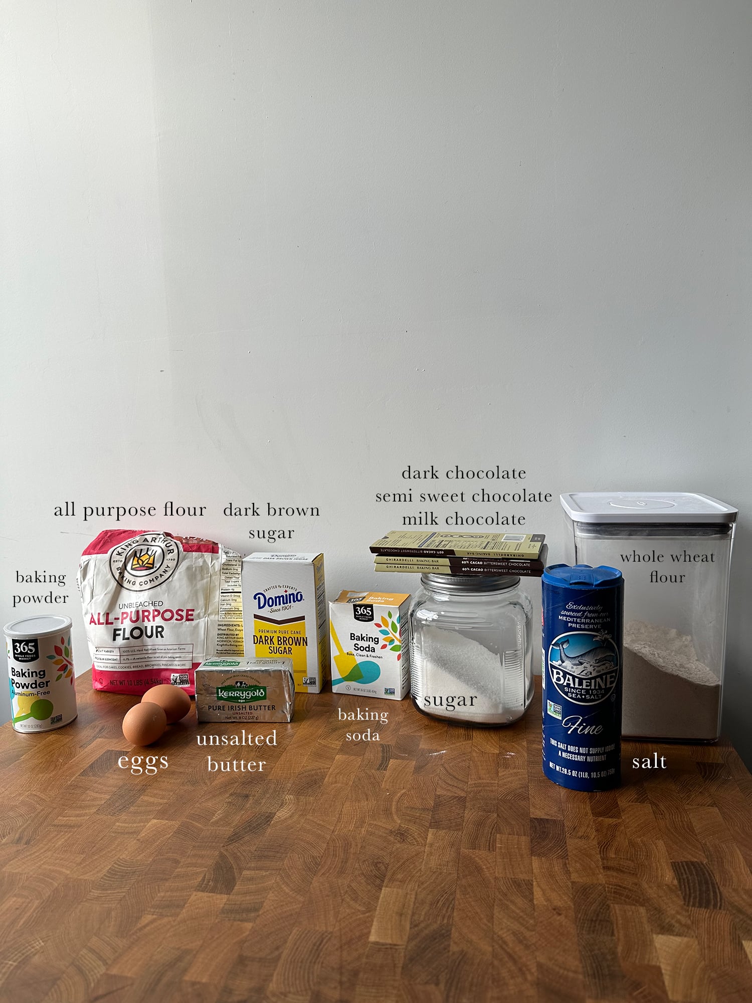 Ingredients needed to make chocolate chip cookies laid out and labeled on a kitchen counter.