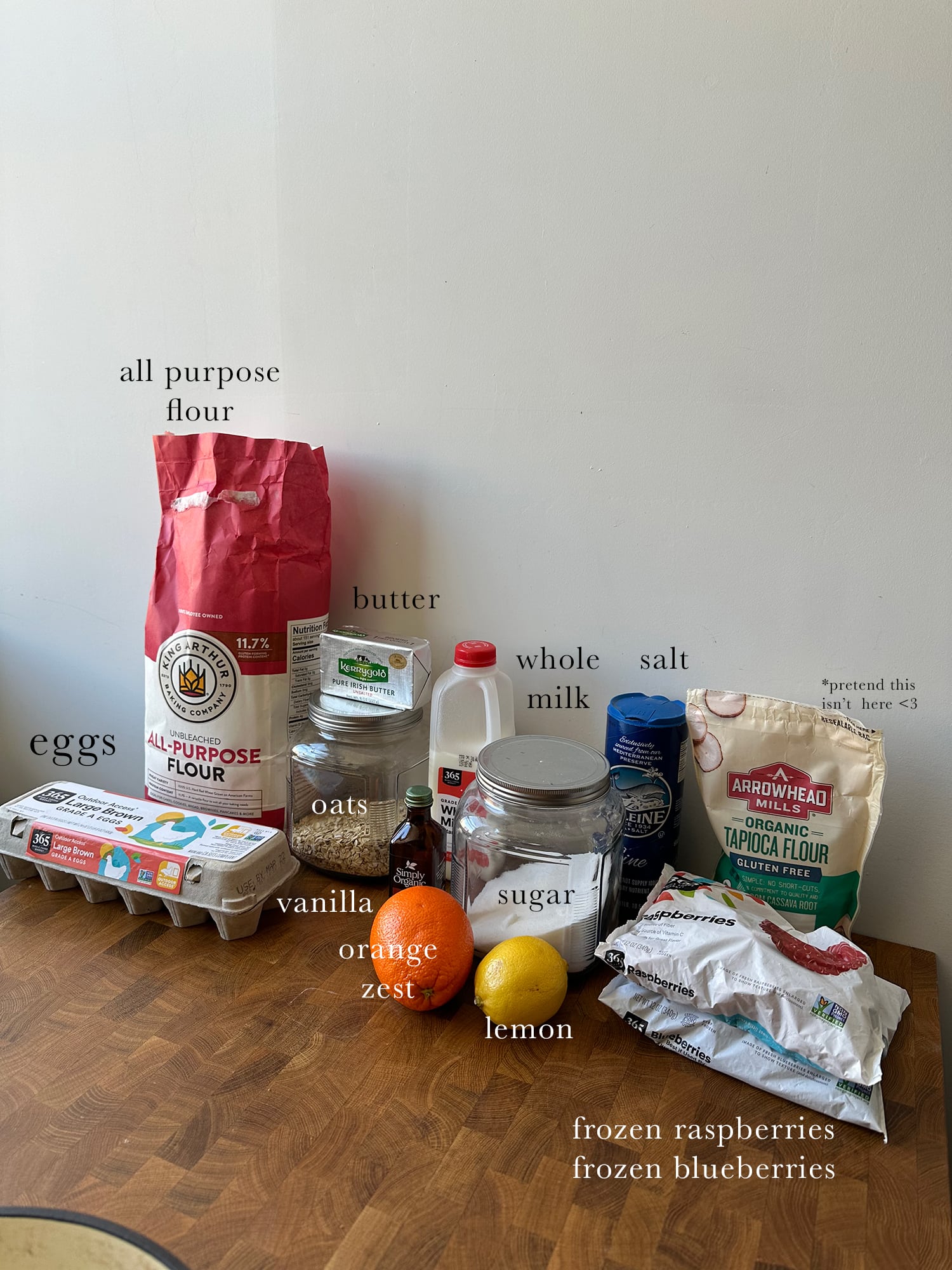 All ingredients needed to make a berry custard cake, laid out and labeled on a kitchen island.