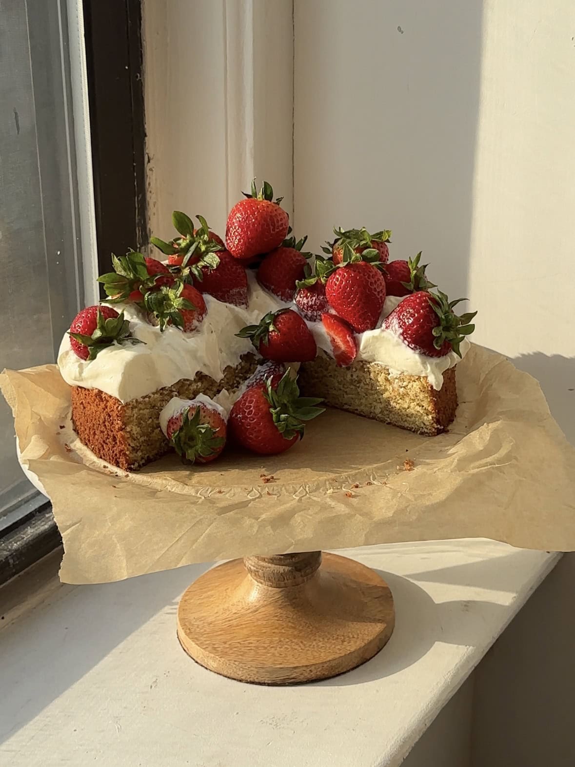 Strawberry Shortcake on a sheet of brown parchment paper on a cake stand. 
