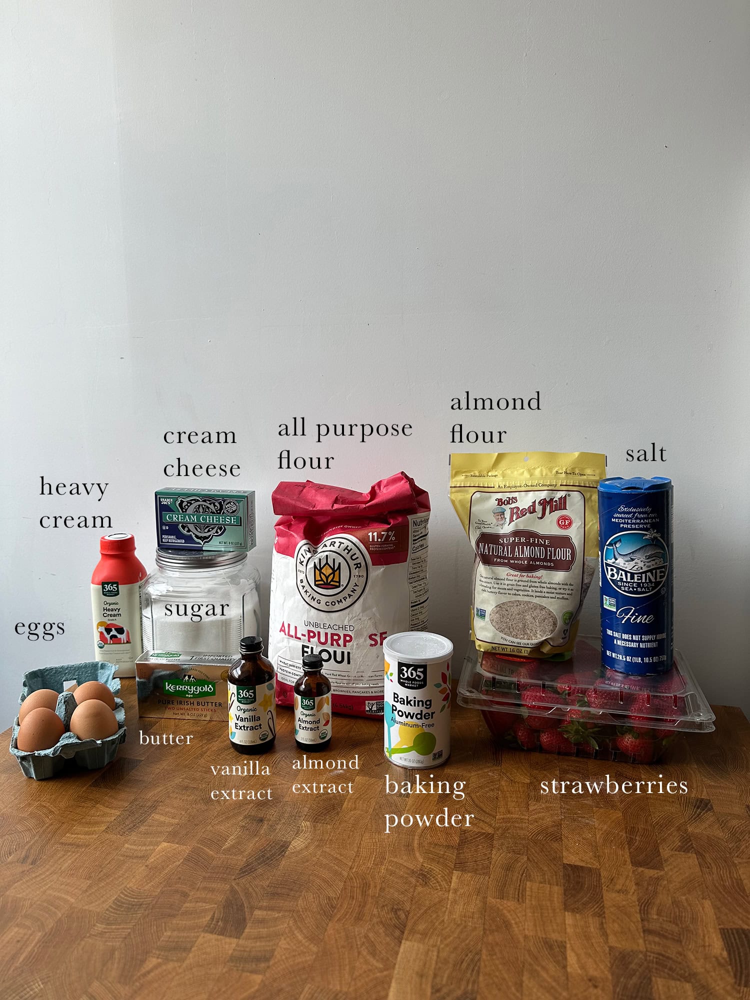 All ingredients needed to make a Strawberry shortcake laid out and labeled on a kitchen island. 