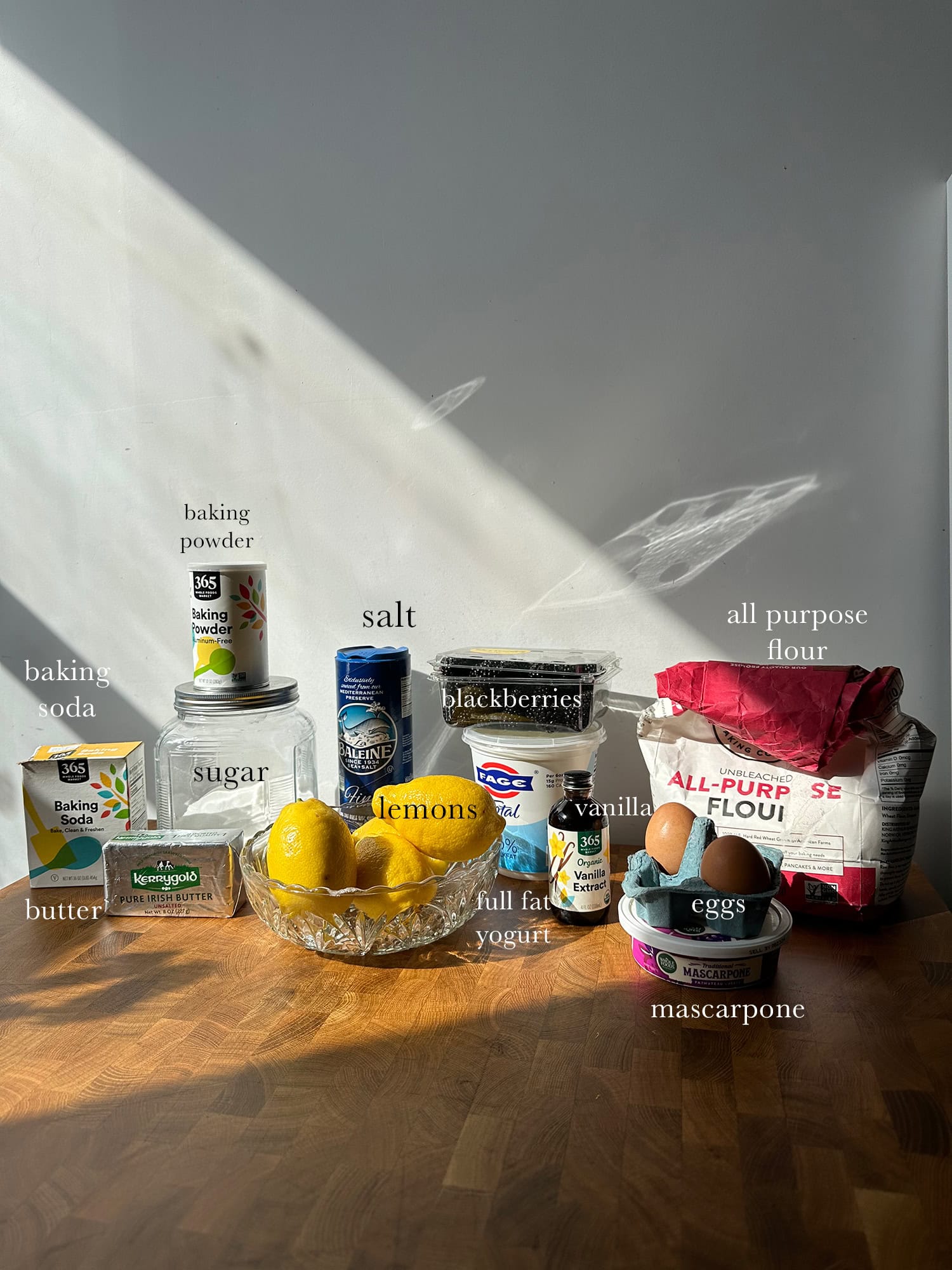 Ingredients needed to make a lemon blackberry cake laid out and labeled on a kitchen island.