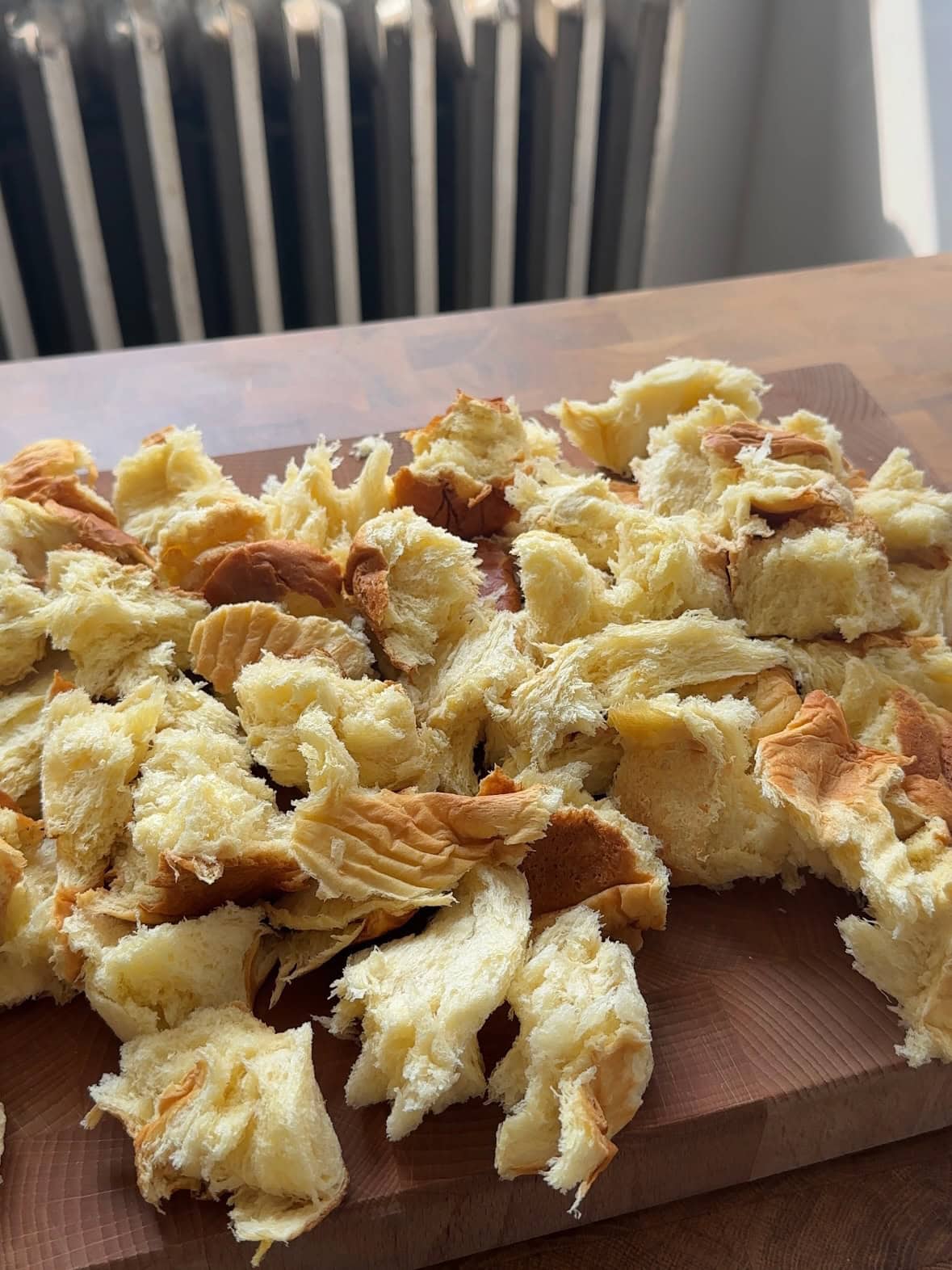 A brioche loaf torn into 1" pieces on a cutting board.