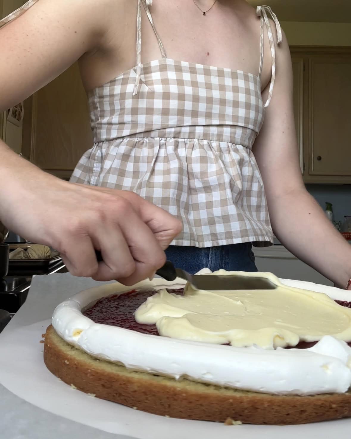 Side view of the lemon curd mascarpone being spread for the filling of a lemon raspberry cake.