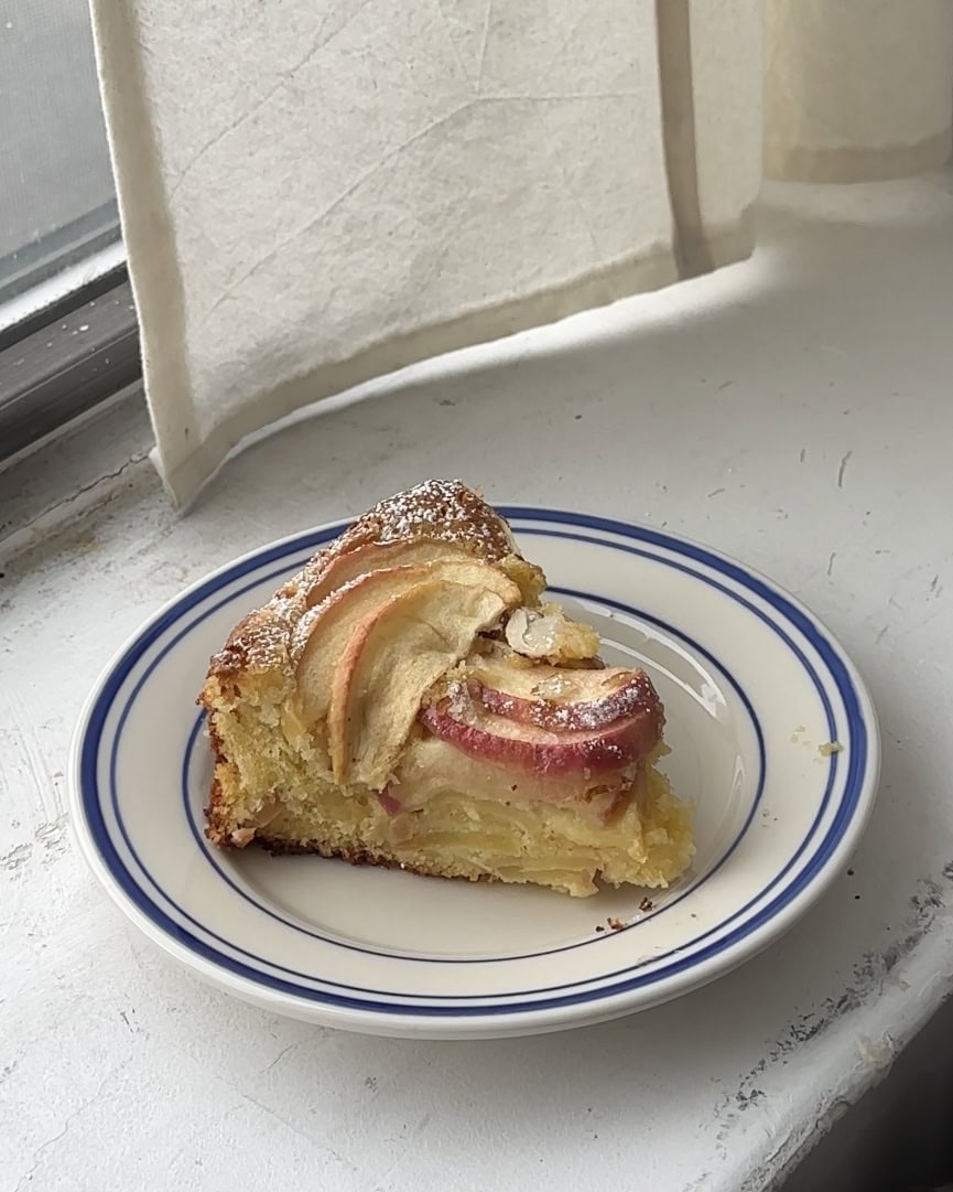 Side view of a slice of apple almond cake on a white and blue plate.