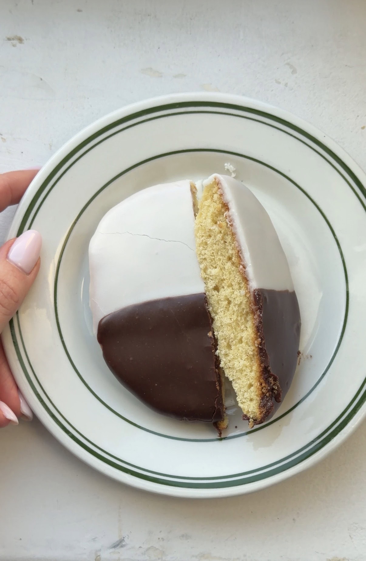 Overhead view of a Black and White cookie cut in half showing the cross section of the cookie.
