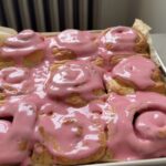 A pan full of Cardamom Blood Orange Buns topped with a blood orange glaze.