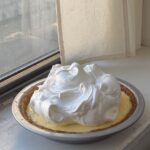 Side view of a full lemon meringue pie topped with a mountain of meringue.