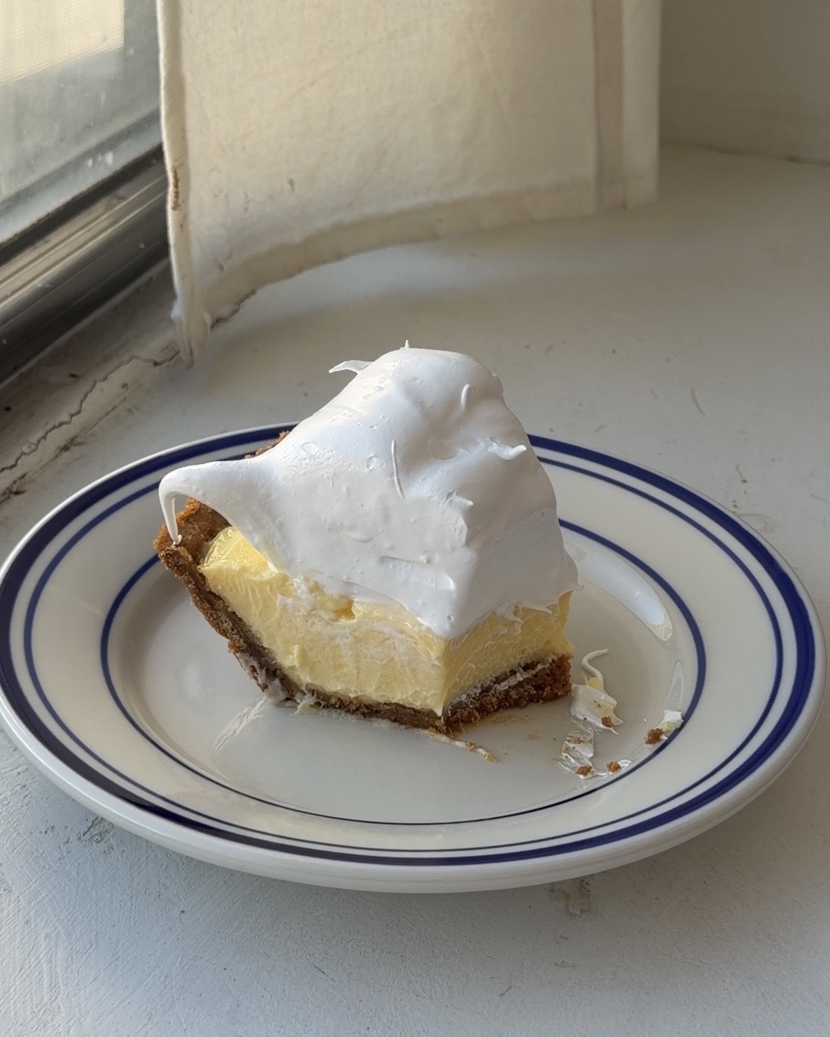 Side view of a slice of lemon meringue pie with a bite taken out of it.