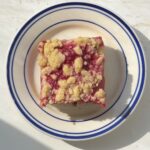 Overhead view of a slice of Rhubarb Raspberry Crumb cake on a white and blue striped plate.