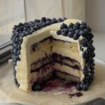 Side view of a lemon blueberry cake with slices taken out showing the layers.