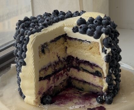 Side view of a lemon blueberry cake with slices taken out showing the layers.